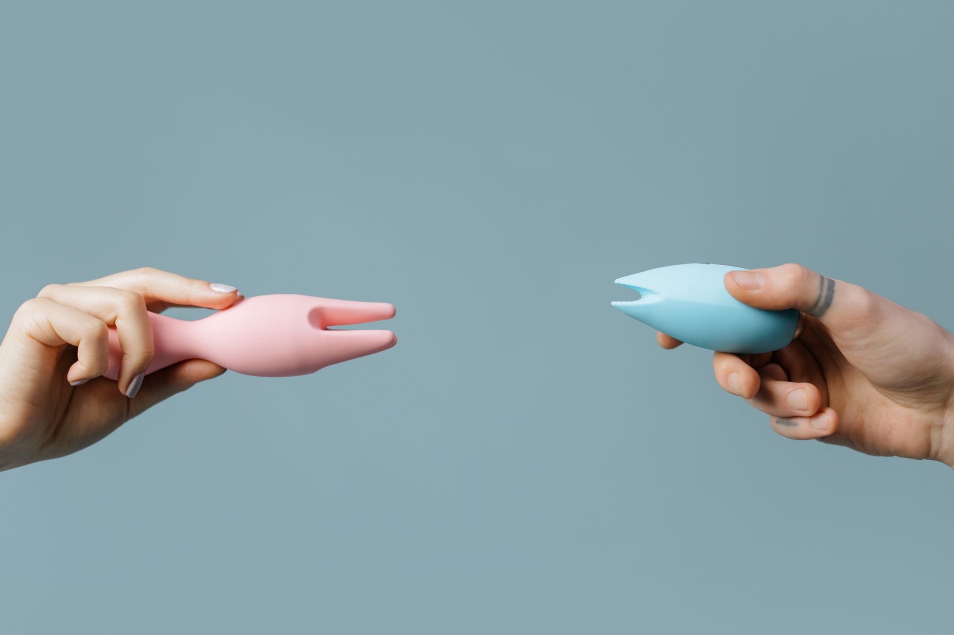 Woman holding colorful silicone vibrators in a thoughtful pose